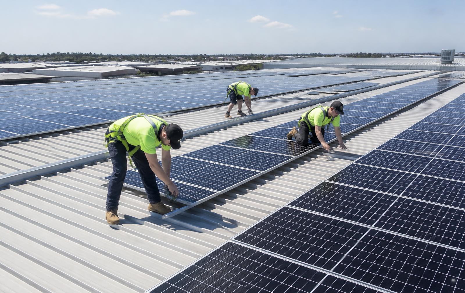 Technicians reviewing installation plans in front of a solar carport and EV chargers